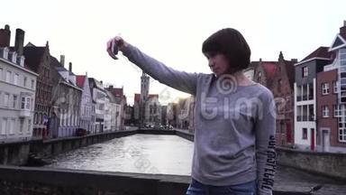 女孩游客在比利时布鲁<strong>日日</strong>落时在智能<strong>手机</strong>上自拍。 慢动作