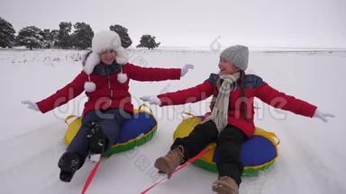 快乐的孩子们在冬天的<strong>雪地</strong>里雪橇，挥舞着他们的手。 孩子们在<strong>雪地</strong>上滑在管子上，欢笑和欢乐