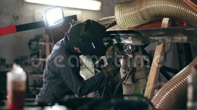 一家焊接厂的男工人戴着焊接面罩，正在从事金属建筑。 在工业工厂焊接
