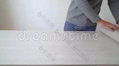 手工工人准备新的壁纸辊，以便在室内<strong>桌面上</strong>做标记