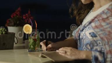 夜间在户外餐厅用记事本写诗歌的灵感女人的手