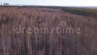 无人机无人驾驶飞机在天空中翱翔，在枯萎的森林和城市的背景上。 剪辑。 重型升降机