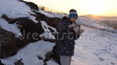 一个年轻的女人在城市附近的山上<strong>喝热水</strong>瓶里的茶或咖啡。