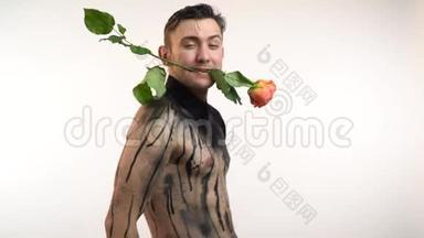 肌肉发达的男人带着玫瑰在牙齿上跳舞，转向镜头