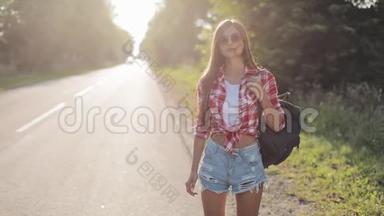 旅行者年轻的女人在阳光明媚的路上搭便车。 年轻女孩想<strong>搭车</strong>开始一段旅程。 夏季
