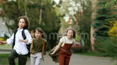 孩子们，男孩和女孩从学校跑出来，挥舞着背包。 有趣的假期。 回学校去。 儿童日