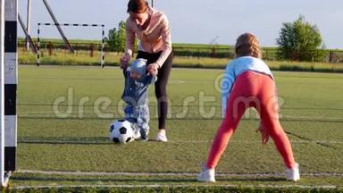 一个快乐的母亲，带着孩子在足球场上踢足球，<strong>进球</strong>，在空中玩耍，生活方式，观念