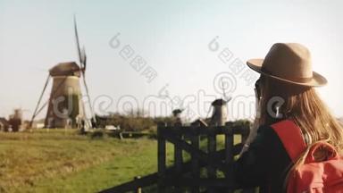年轻摄影师拍一张旧风车的照片。 戴着红色背包的女博客。 记者。 记者。 4K.