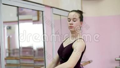 穿紫色紧身衣的年轻芭蕾舞演员优雅地表演某种芭蕾舞动作，阿巴格，站在镜子旁的巴雷