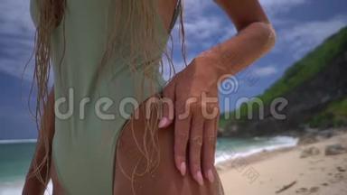 海滩上一个戴草帽的女孩的特写镜头，她的手从大腿跑到胸部，从底部缓慢拍摄