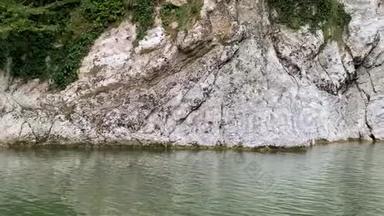 一条高高的瀑布从悬崖上跌入清澈的湖面。 俄罗斯索契