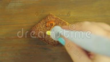一只手拿着一管烹饪颜料，在巧克力饼干上画了三根黄色的颜料