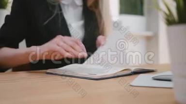漂亮的金发女郎套装，坐在书桌前，用笔在记事本上写字，<strong>翻页</strong>，抽出床单