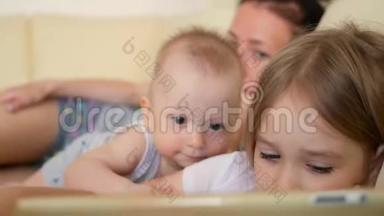 家庭观念。 姐姐和<strong>弟弟</strong>在房间的沙发上用平板电脑。 充满爱意的家庭。 年轻母亲