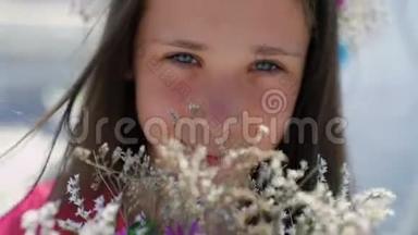 女孩的特写肖像`她的脸嗅着花。 慢慢地