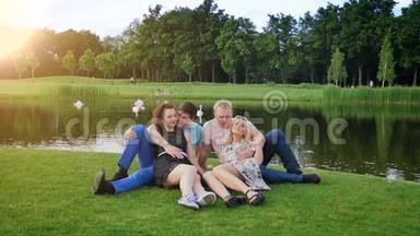 公园里两对夫妇坐在河边接吻的慢动作视频