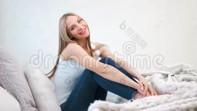 迷人的、微笑的赤脚女人坐在舒适的家中尽情享受