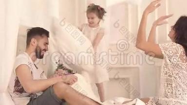 幸福的三口之家：母亲、父亲和女儿在床上打枕头仗