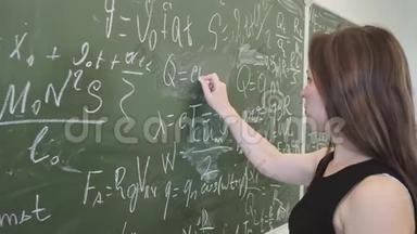 女学生在黑板上写下数学公式，并在摄像机前摆出姿势
