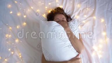 三合一视频。 困倦的女孩用枕头遮住脸。 在床上玩枕头