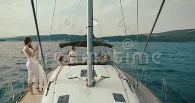 女人在游艇上放松。 穿着白色<strong>连衣裙</strong>的<strong>女士</strong>沿着游艇走着，风在湖面上吹着她的<strong>连衣裙</strong>