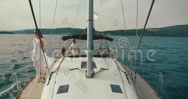 女人在游艇上放松。 穿着白色<strong>连衣裙</strong>的<strong>女士</strong>沿着游艇走着，风在湖面上吹着她的<strong>连衣裙</strong>