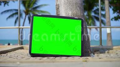 电视站在海滩上。 带有绿色屏幕的电视。 你可以用你想要的镜头或图片<strong>替换</strong>绿色屏幕