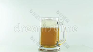 啤酒被<strong>倒入</strong>一个玻璃<strong>杯中</strong>，沿着墙壁泡沫在白色的背景上排出
