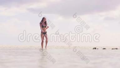 穿着泳衣的布鲁内特<strong>女士</strong>在热带海滩的海水中散步。 穿着<strong>比基尼</strong>在清水上行走的漂亮女人