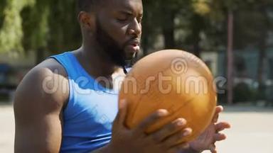 严肃的黑人一个人坐在体育场，扔球，准备比赛