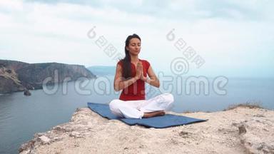 女孩坐在海边的岩石上，冥想莲花瑜伽姿势，集中注意力，放松<strong>心灵</strong>，灵魂和身体。