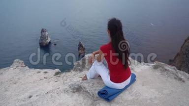 女孩坐在海边的岩石上，冥想莲花瑜伽姿势，集中注意力，放松<strong>心灵</strong>，灵魂和身体。