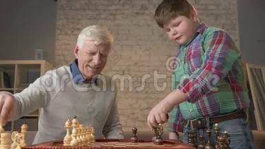 爷爷和孙子正准备<strong>下棋</strong>。 一个<strong>老人</strong>教一个胖孩子如何<strong>下棋</strong>。 暴露在