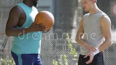 两位多种族的运动员朋友在体育场讨论最后一场篮球比赛
