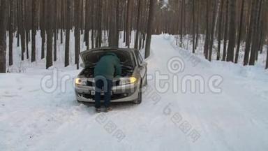 冬天，一个人修理一辆破汽车。一名男子站在打开的汽车引擎盖旁，正在寻找破损处。