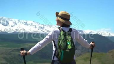 那个带着绿色背包的旅行者的女人在山上<strong>花钱</strong>，看着白色的山脉。