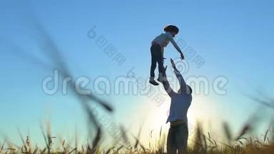 夏日里父子在麦田里<strong>嬉戏</strong>，欣赏日落的剪影。 幸福的家庭散步