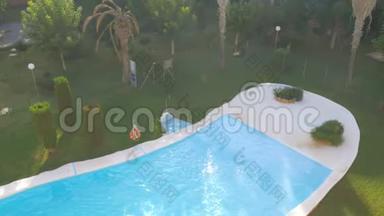 在阳光明媚的夏日，豪华的室外游泳池配有蓝色的水和阳光反射。 顶部视图