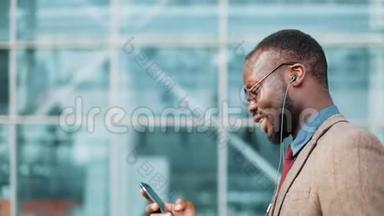 非洲裔美国商人戴着太阳镜在办公楼附近用耳机<strong>打电话</strong>。 <strong>商务</strong>