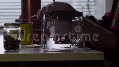 盖伊在桌子上用大杯子和玻璃茶壶做卷烟。