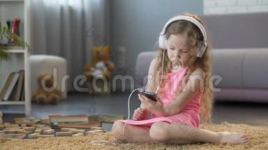 戴着耳机的孩子在智能手机上听音乐，沉迷于科技