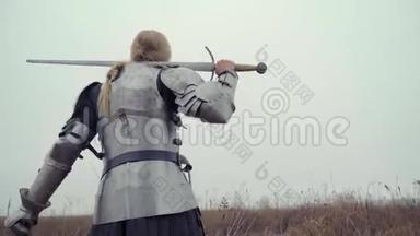 珍妮德`身穿铠甲，肩上有剑的弧形站在田野里，寻找敌人