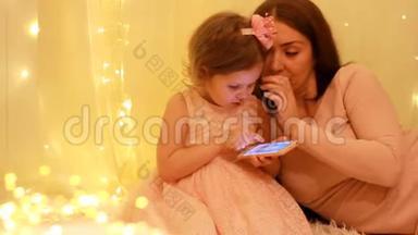 妈妈带着小女孩看手机屏幕，玩下载的应用程序。
