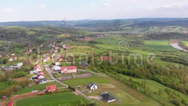 在一个有小房子的村庄里，空中无人机可以看到绿田、丘陵和树木。 波兰。