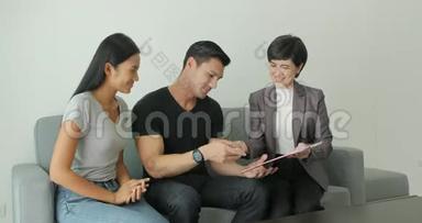 年轻有魅力的夫妇会见房地产经纪人，与女经纪人签订合同。