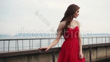 美丽的女人享受着凉风，<strong>吹拂</strong>着她鲜红的裙子和头发