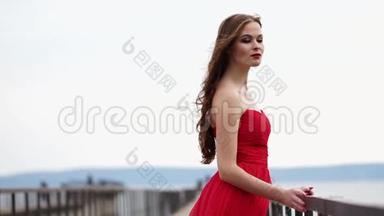 一位漂亮的女士喜欢风，吹拂着她鲜红的长裙和卷发