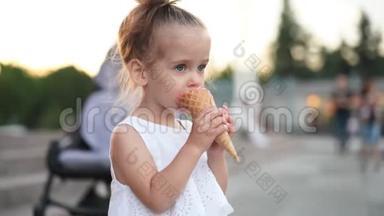 可爱的白种人小女孩喜欢在公园散步的华夫饼锥冰淇淋。 孩子吃明亮的冰淇淋