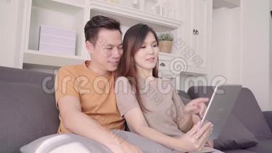 亚洲夫妇使用平板电脑视频电话与朋友在客厅在家里。