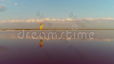 一个孤独的风筝手在粉红色的湖面上，白云上控制着一只训练风筝